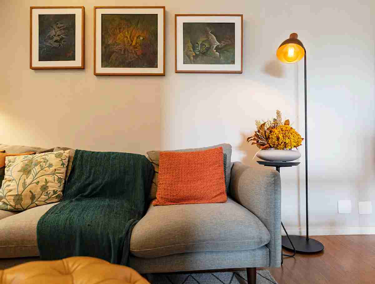 O ambiente possui luminária de piso com luz quente, além de almofadas e mantinhas no sofá / Projeto de Tatiane Waileman e foto de Emerson Rodrigues